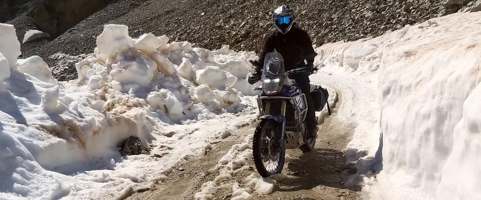 Motorcycle riding along track with deep snow on side of track