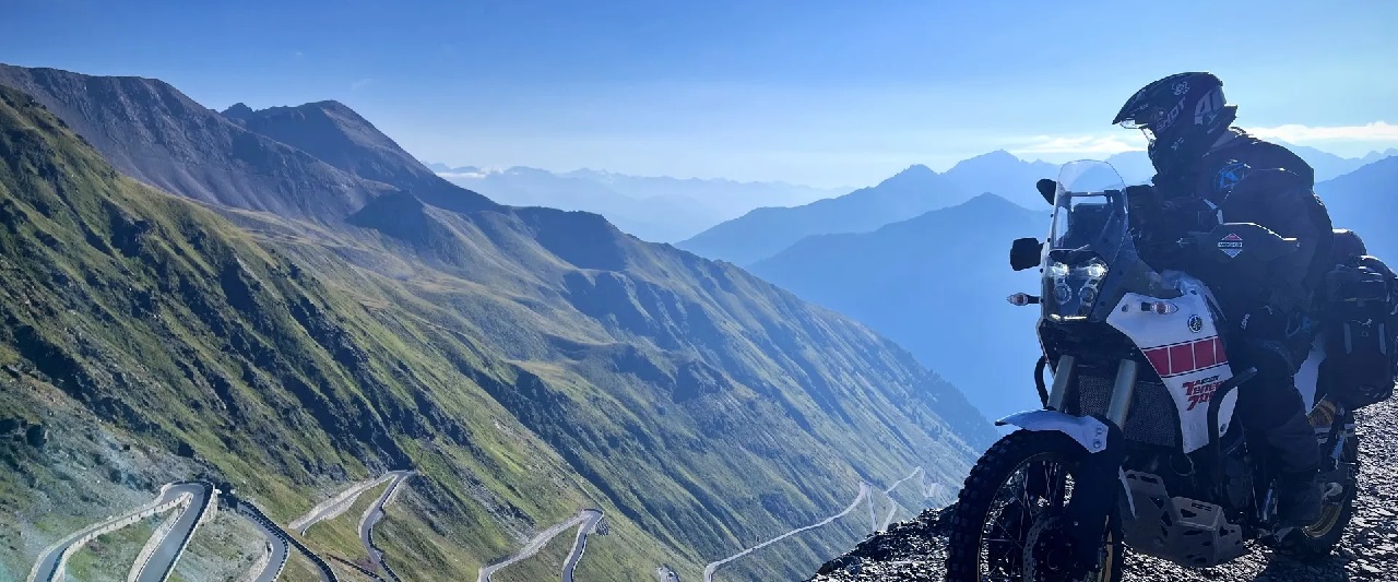 Rider looks down on road with hairpin bends leading up the mountain